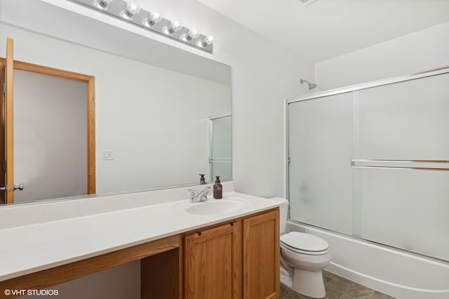 full bathroom featuring combined bath / shower with glass door, vanity, and toilet