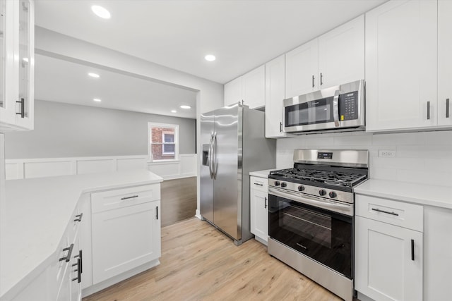 kitchen featuring backsplash, white cabinetry, light hardwood / wood-style flooring, and appliances with stainless steel finishes