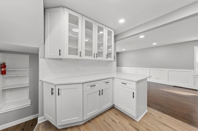 kitchen with kitchen peninsula, white cabinetry, and light wood-type flooring