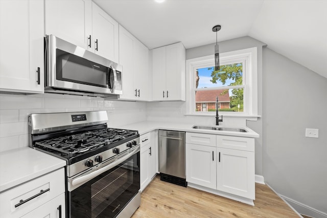 kitchen featuring white cabinets, light hardwood / wood-style flooring, appliances with stainless steel finishes, and vaulted ceiling