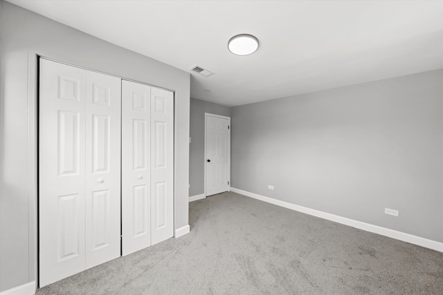 unfurnished bedroom with a closet and light colored carpet