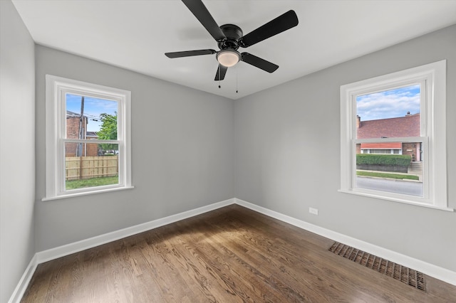 unfurnished room featuring dark hardwood / wood-style floors, ceiling fan, and a wealth of natural light