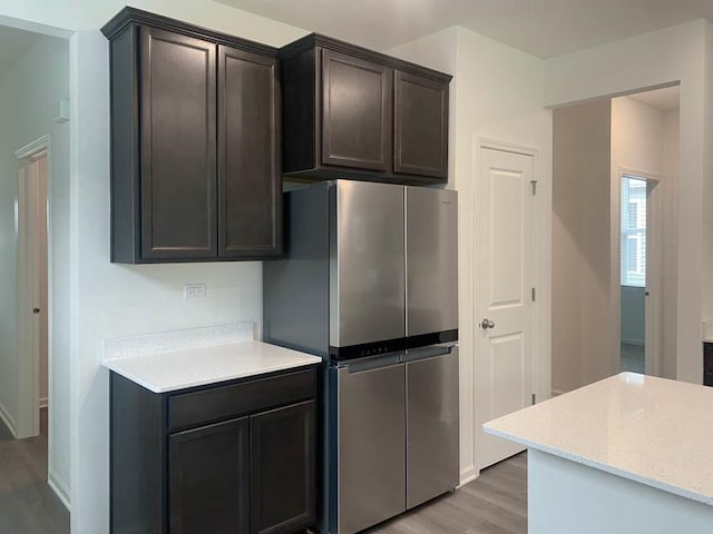 kitchen featuring stainless steel fridge, dark brown cabinetry, and light wood-type flooring