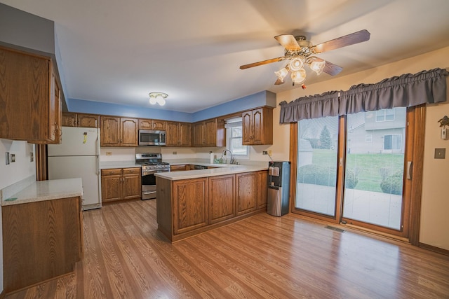 kitchen with sink, ceiling fan, light wood-type flooring, kitchen peninsula, and stainless steel appliances