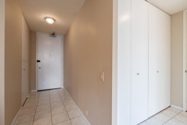 hallway with a textured ceiling and light tile patterned flooring