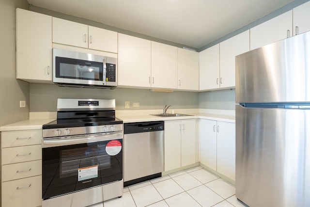 kitchen with white cabinets, light tile patterned floors, sink, and appliances with stainless steel finishes