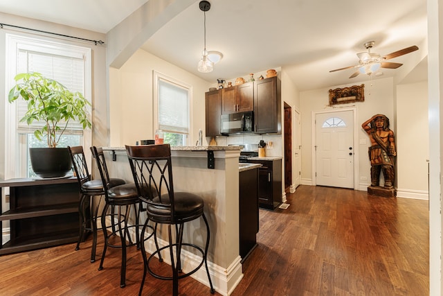 kitchen featuring pendant lighting, a breakfast bar, dark wood-type flooring, and a wealth of natural light