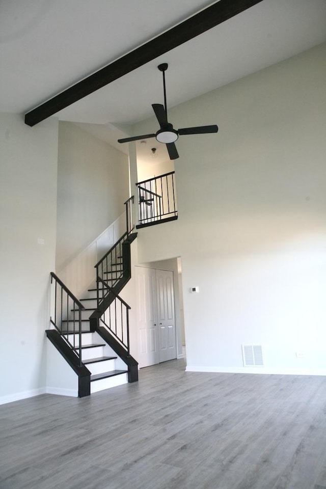 stairway with beam ceiling, hardwood / wood-style flooring, high vaulted ceiling, and ceiling fan