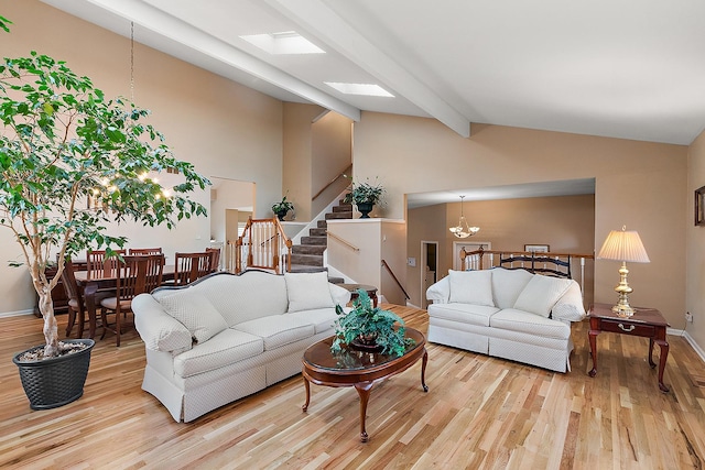 living room featuring a skylight, beam ceiling, high vaulted ceiling, light hardwood / wood-style flooring, and a chandelier