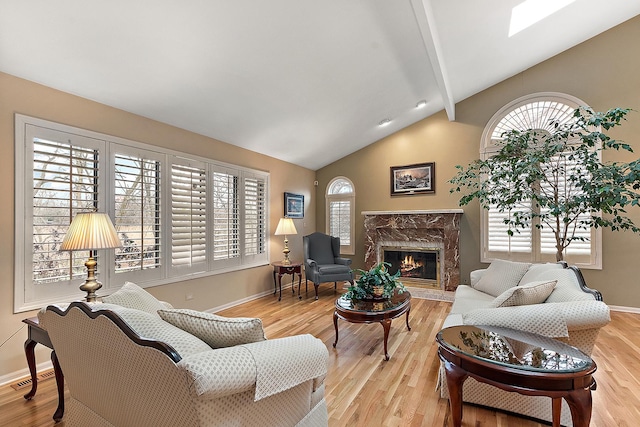 living room featuring lofted ceiling with skylight, a fireplace, and light wood-type flooring