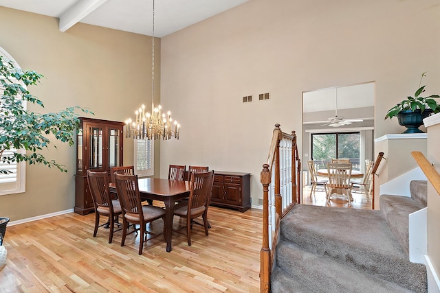 dining space with ceiling fan with notable chandelier, light hardwood / wood-style floors, beam ceiling, and high vaulted ceiling