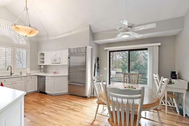 kitchen featuring white cabinetry, sink, built in appliances, pendant lighting, and light wood-type flooring