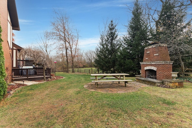 view of yard featuring an outdoor brick fireplace and a patio