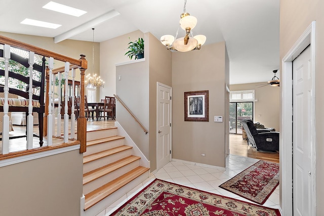 entryway featuring ceiling fan with notable chandelier, light tile patterned flooring, and vaulted ceiling