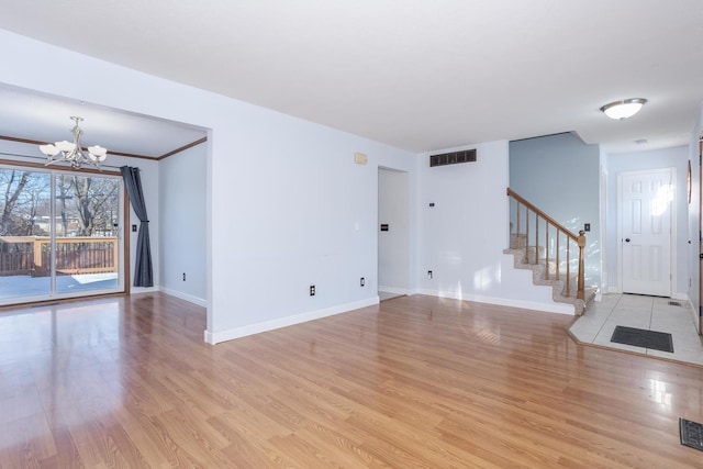 unfurnished living room featuring an inviting chandelier and light hardwood / wood-style floors