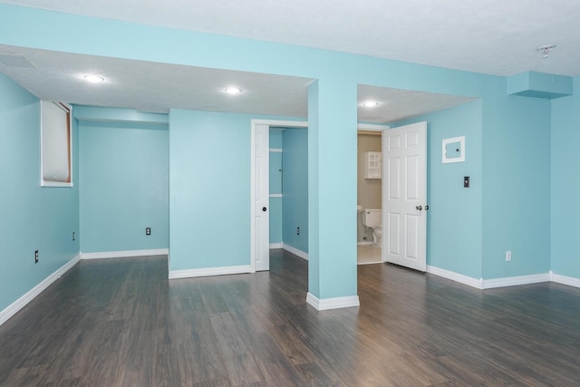 basement with a textured ceiling and dark hardwood / wood-style flooring