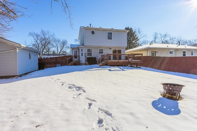 snow covered house featuring a fire pit and a wooden deck