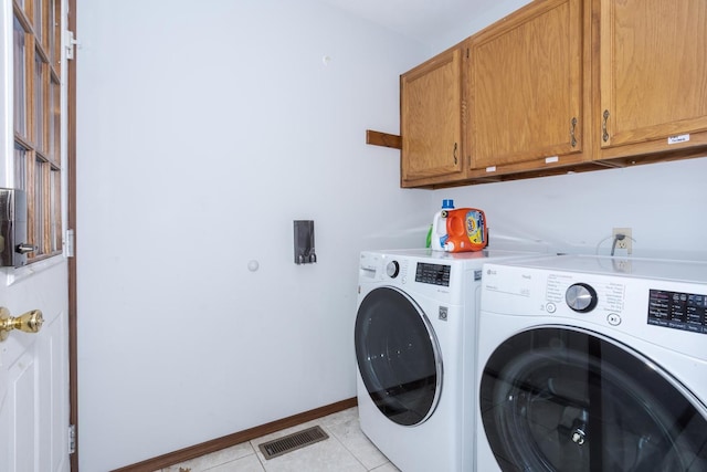 washroom featuring cabinets, washing machine and clothes dryer, and light tile patterned floors