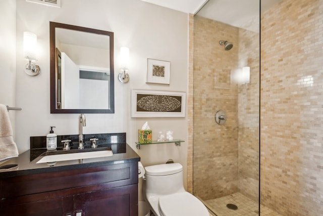 bathroom featuring a tile shower, vanity, and toilet