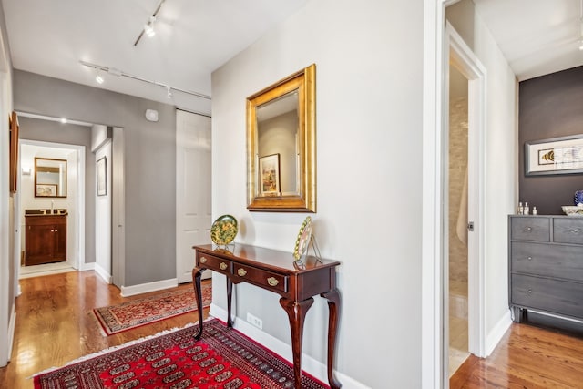 hall with hardwood / wood-style floors and rail lighting