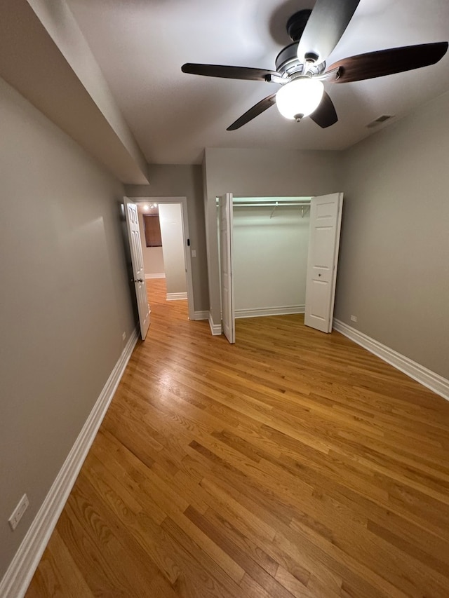 unfurnished bedroom featuring ceiling fan, light wood-type flooring, and a closet