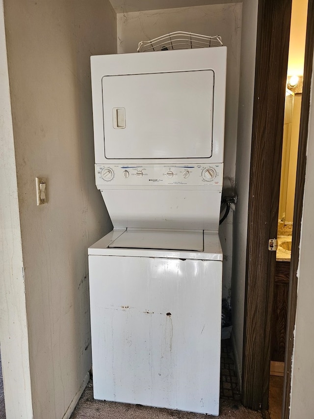 clothes washing area featuring stacked washer / drying machine and carpet floors