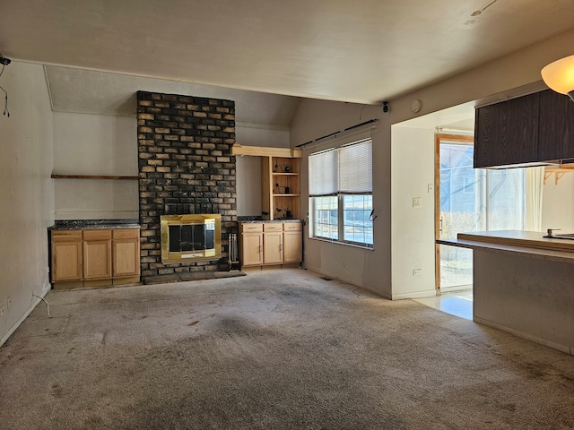 unfurnished living room with a fireplace, light colored carpet, and vaulted ceiling