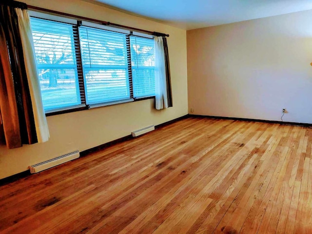 spare room with baseboard heating and light hardwood / wood-style flooring