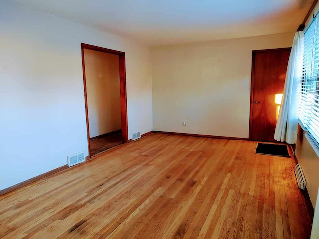 empty room with a baseboard heating unit and light wood-type flooring