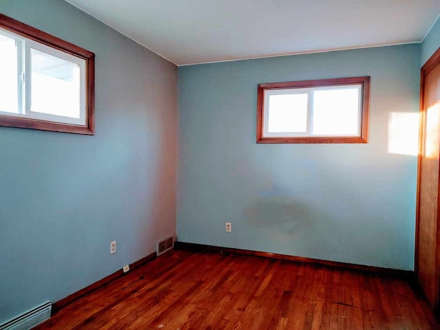 spare room with dark wood-type flooring and a baseboard radiator