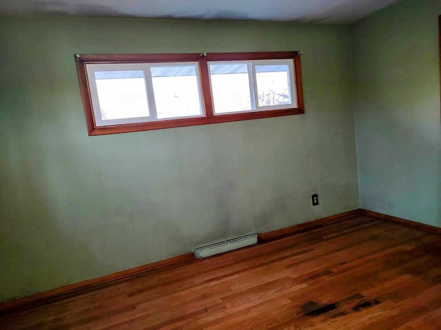 unfurnished room featuring a baseboard heating unit and wood-type flooring