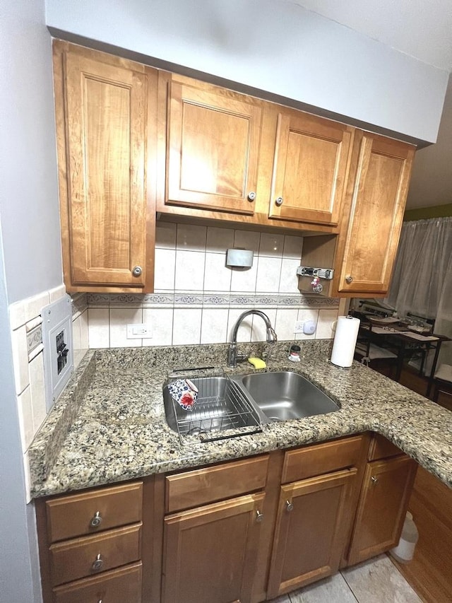 kitchen with backsplash, stone counters, and sink