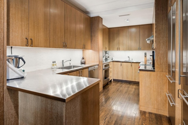 kitchen featuring kitchen peninsula, stainless steel appliances, stainless steel counters, dark wood-type flooring, and sink