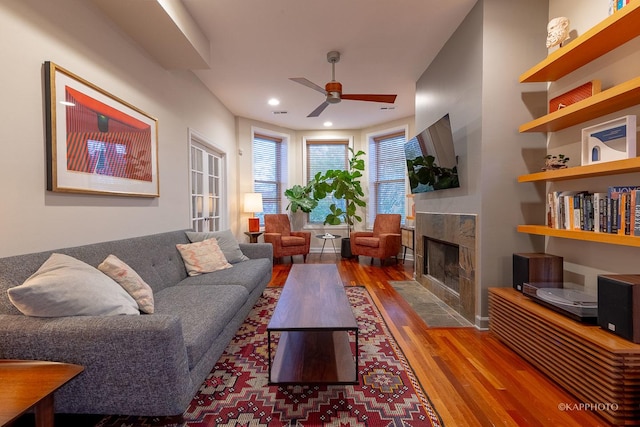 living room featuring ceiling fan, wood-type flooring, and a fireplace