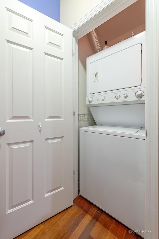 clothes washing area featuring light wood-type flooring and stacked washer / dryer