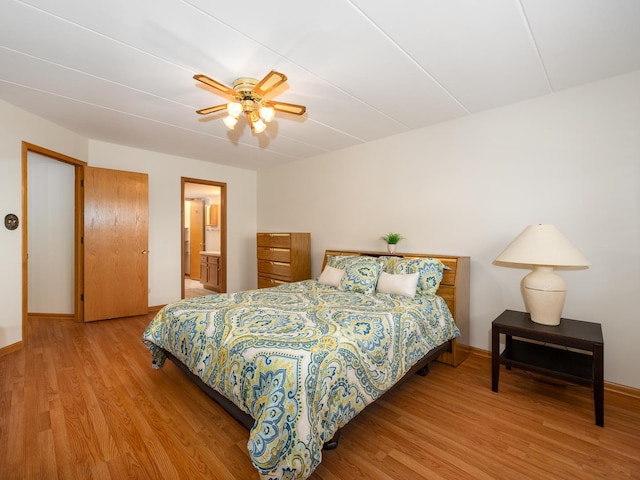 bedroom with connected bathroom, ceiling fan, and light hardwood / wood-style flooring