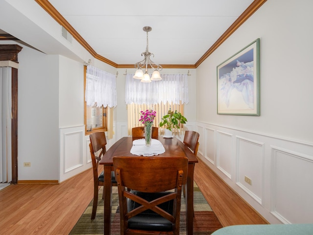 dining area with ornamental molding, light hardwood / wood-style flooring, and a notable chandelier