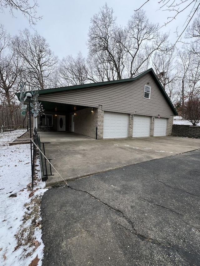 snow covered garage with a carport