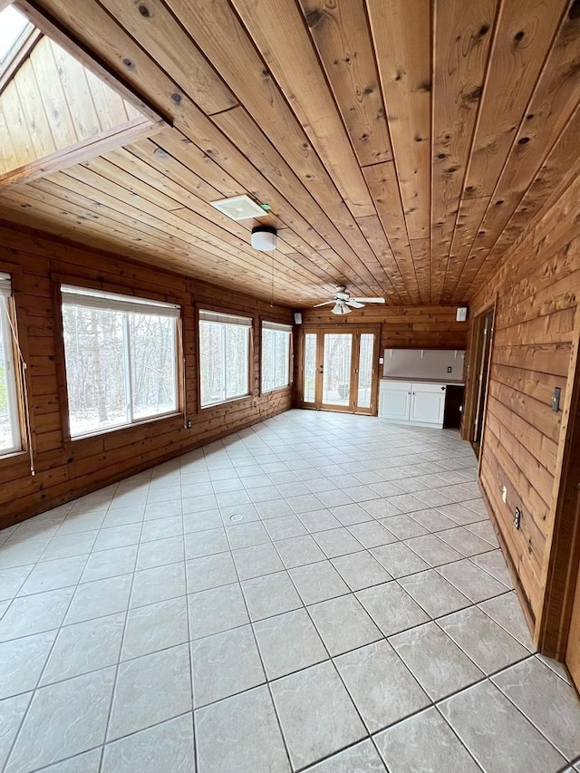 tiled spare room featuring ceiling fan, plenty of natural light, wood walls, and wood ceiling