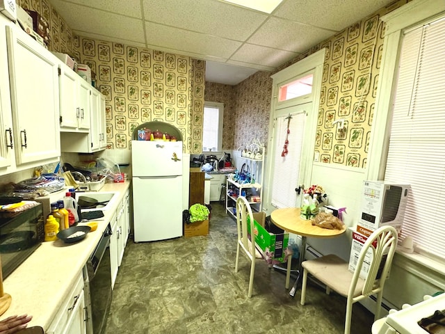 kitchen featuring a drop ceiling, white fridge, white cabinetry, and black dishwasher