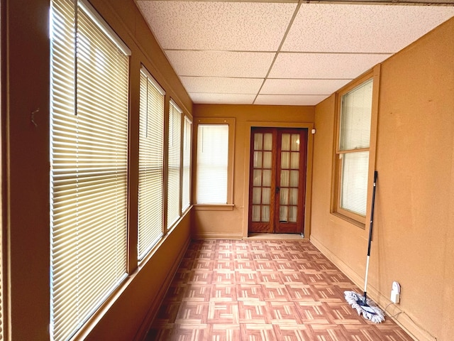 unfurnished sunroom featuring a drop ceiling and french doors