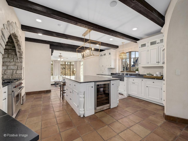 kitchen with high end range, white cabinets, beverage cooler, and a healthy amount of sunlight