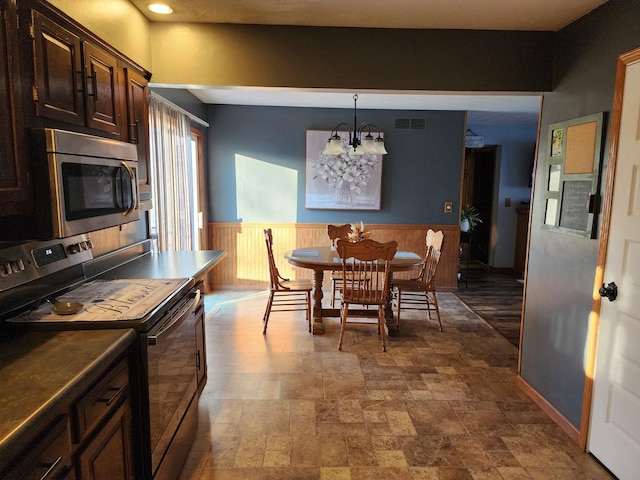 kitchen with stainless steel appliances, a chandelier, dark brown cabinetry, and decorative light fixtures