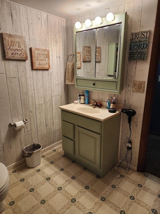 bathroom featuring vanity, wooden walls, and toilet