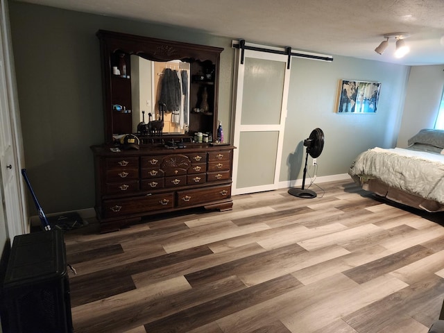 bedroom with a barn door and light hardwood / wood-style flooring