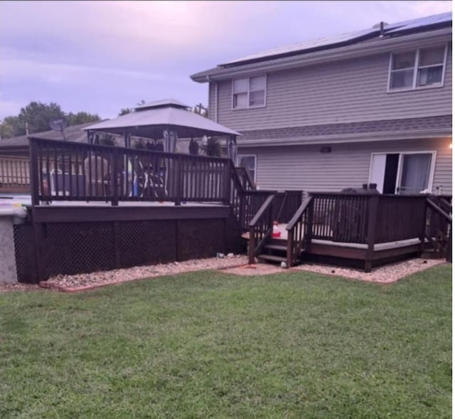 rear view of property featuring a gazebo, a yard, and a deck