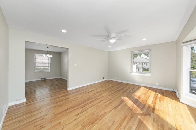 unfurnished room featuring ceiling fan with notable chandelier and light hardwood / wood-style floors