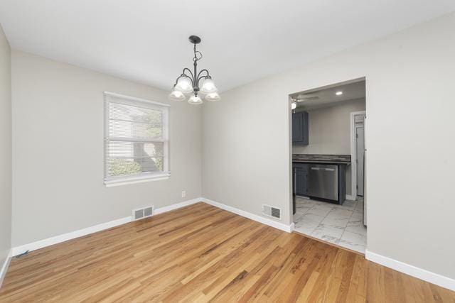 unfurnished dining area featuring light hardwood / wood-style floors and an inviting chandelier