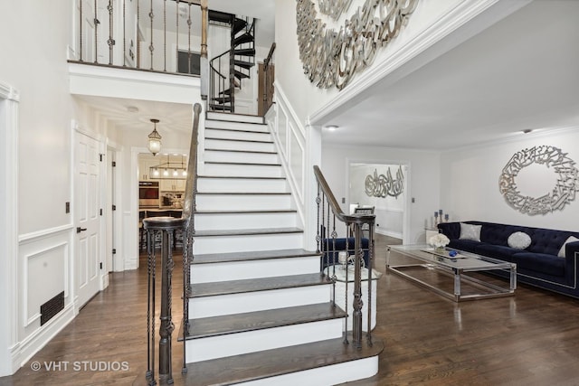 staircase with crown molding, a high ceiling, and hardwood / wood-style flooring