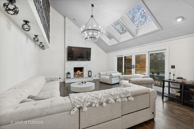 living room featuring dark hardwood / wood-style flooring, a skylight, high vaulted ceiling, and a stone fireplace